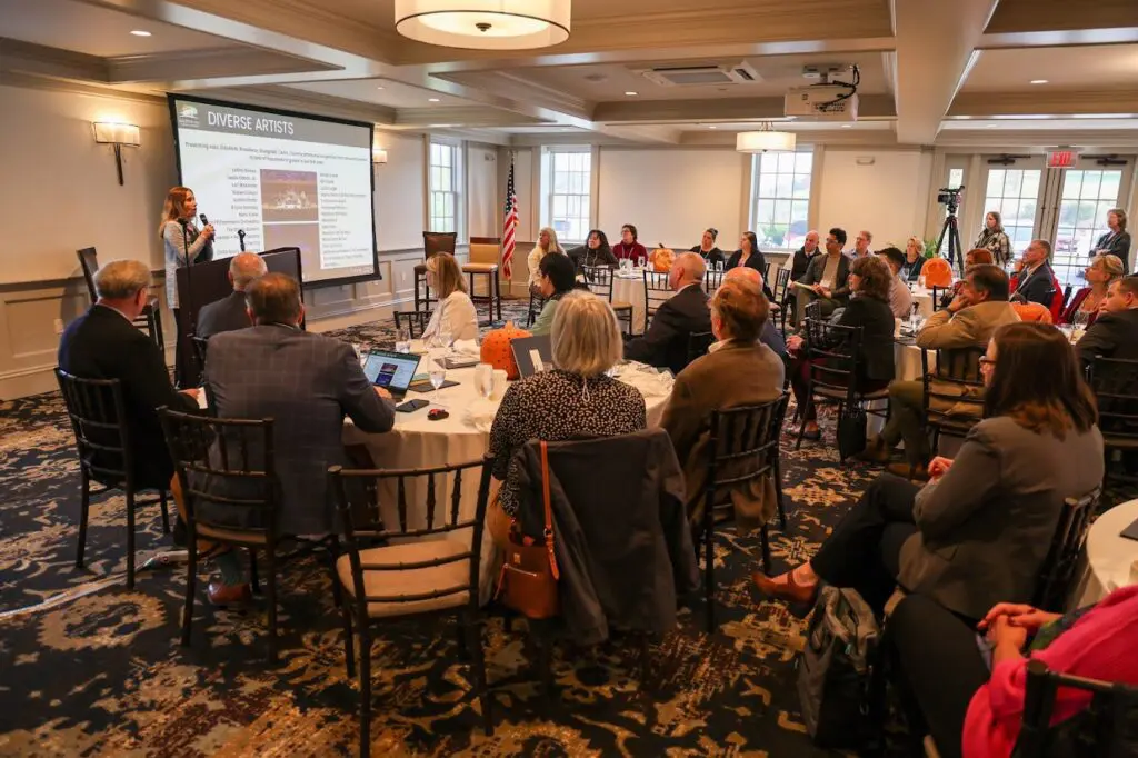 Groton hosts regional tourism conference with a group of people sitting around a table in a room.