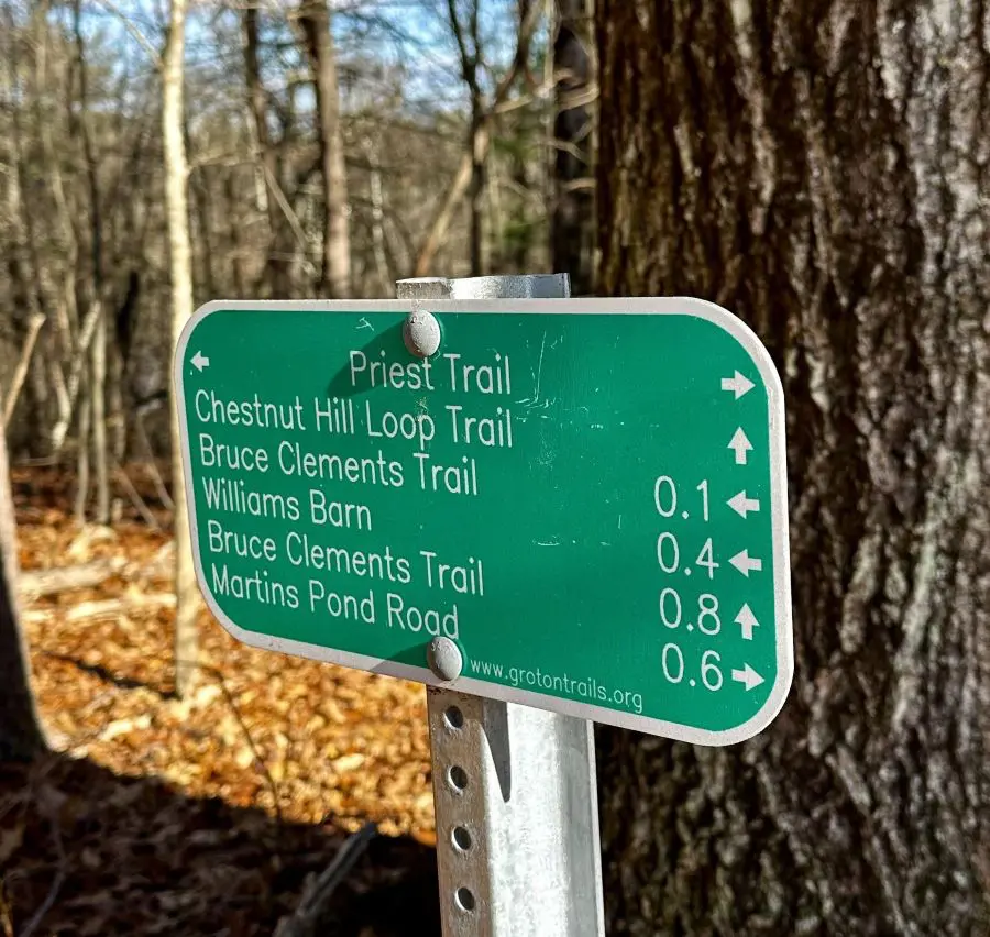 Green trail sign with distances and arrows.