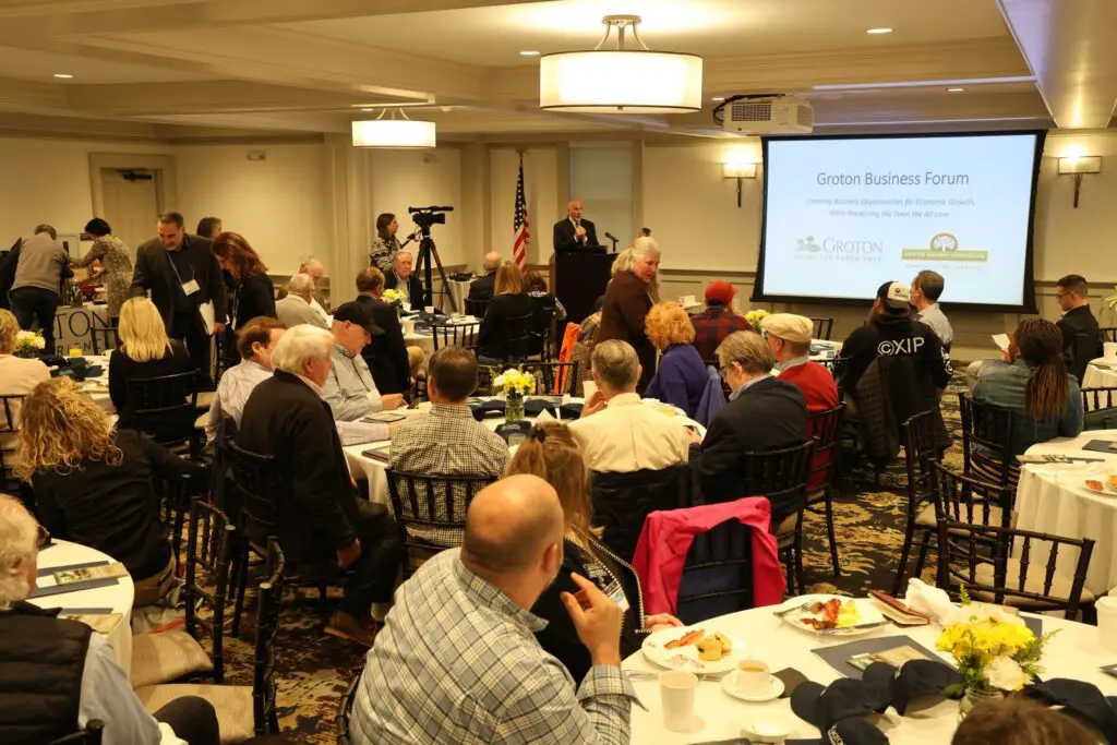 People attend a business forum in a room.